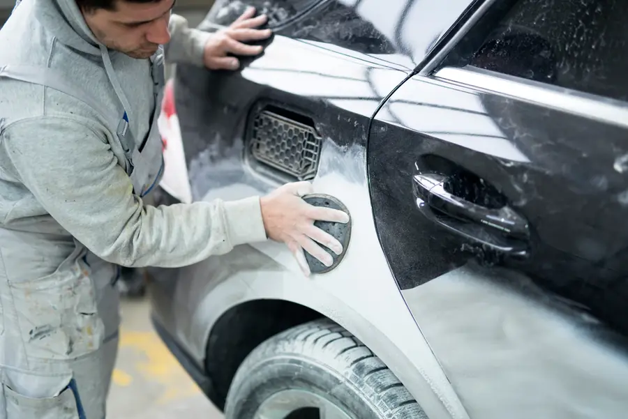 Profissional reparando a lataria de um carro cinza
